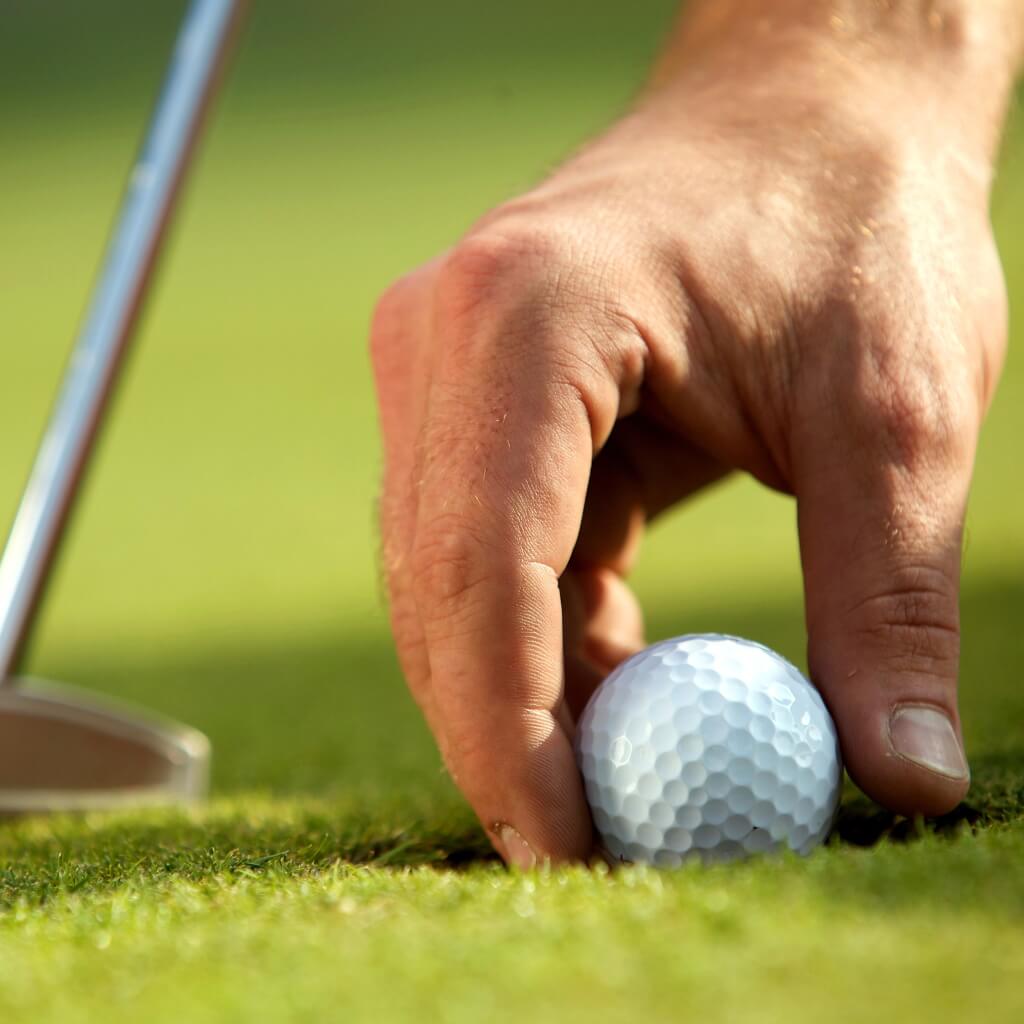 Hand mit Golfball und Golfschläger