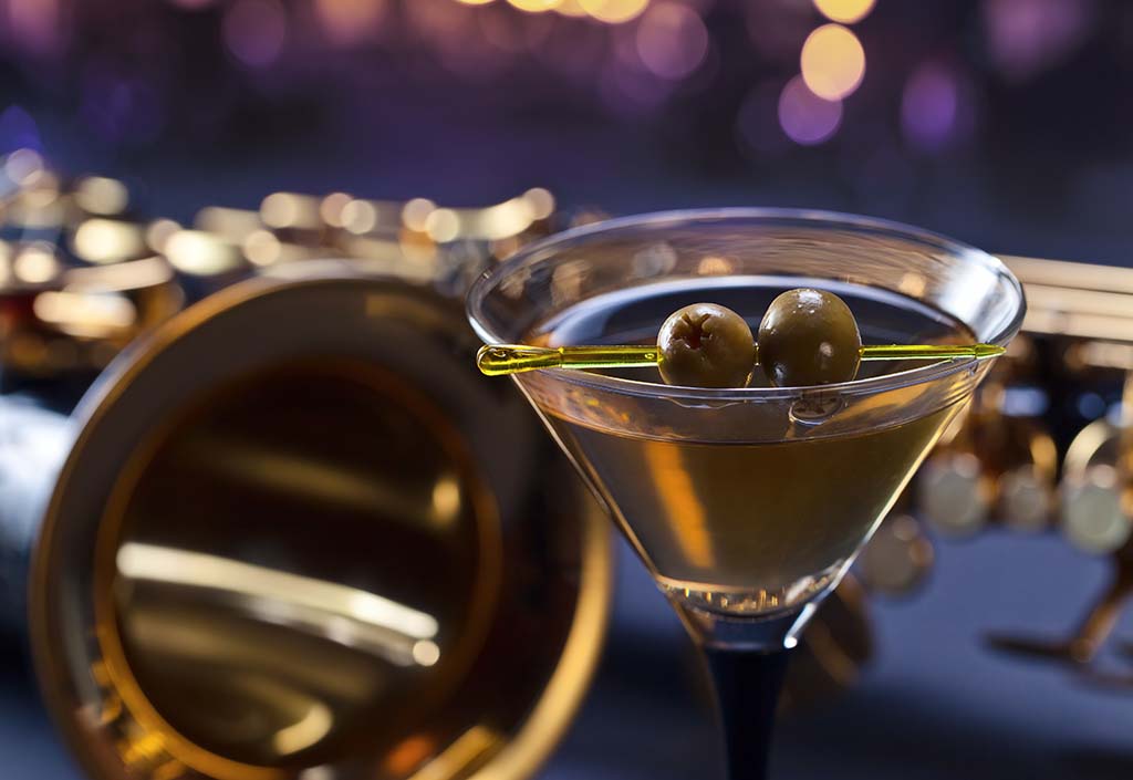 martini with green olives and saxophone, focus on foreground