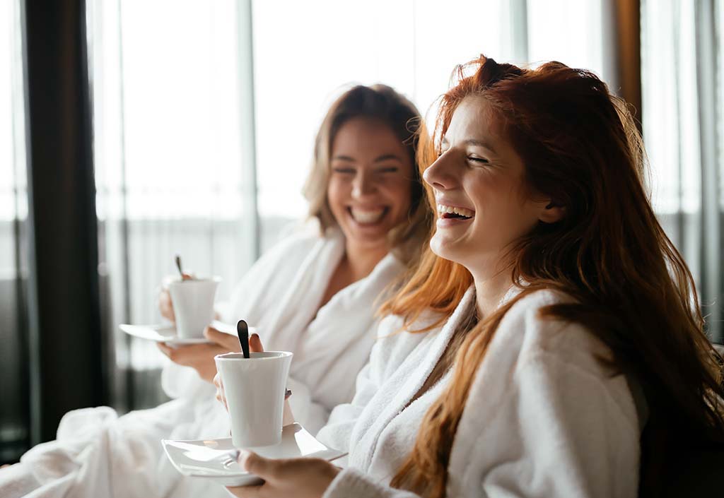 Women in bathrobes enjoying tea during wellness weekend